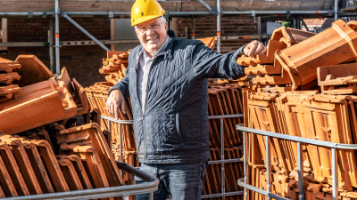 Bouwvakker staat op een bouwplaats tussen allemaal dakpannen