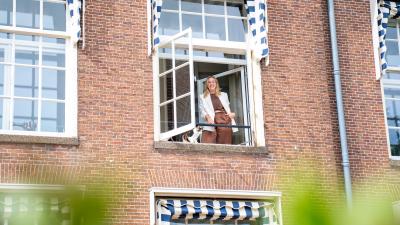 Bewoner van historisch gebouw Wissesdwinger in Leeuwarden voor het open raam 