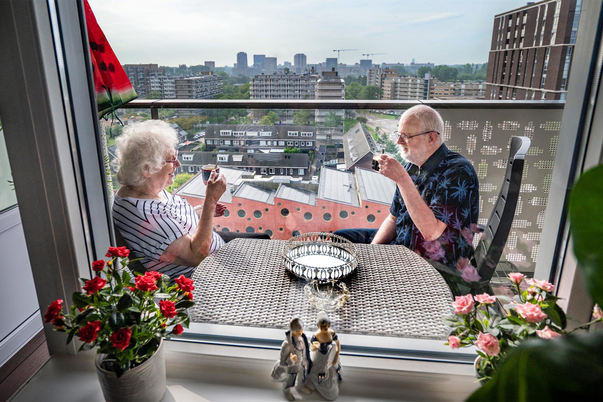 Ouder echtpaar op balkon in seniorenflat in de Statenjachtstraat in Amsterdam-Noord 