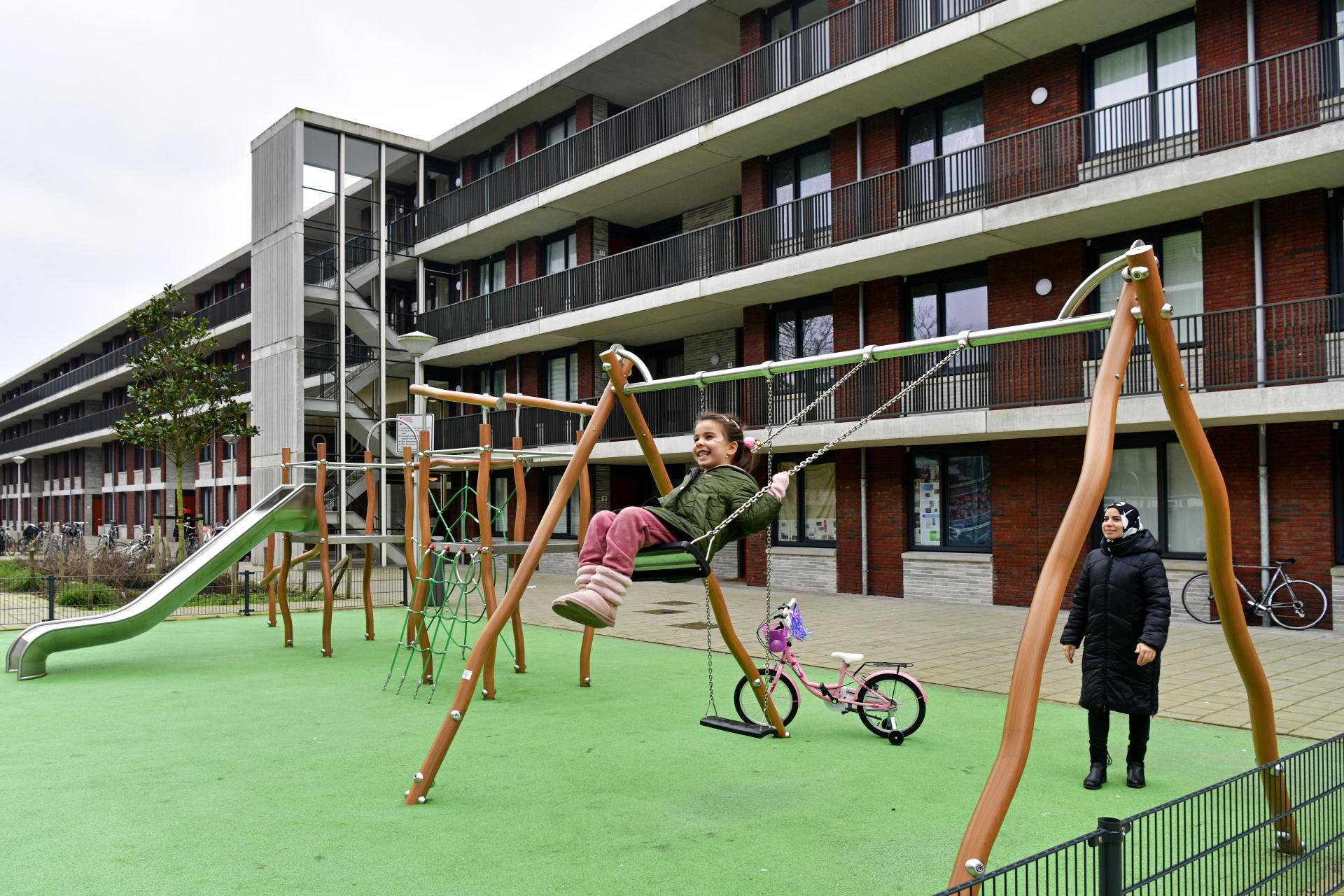 Foto van een kind in de speeltuin bij een appartementencomplex in de Bakemabuurt