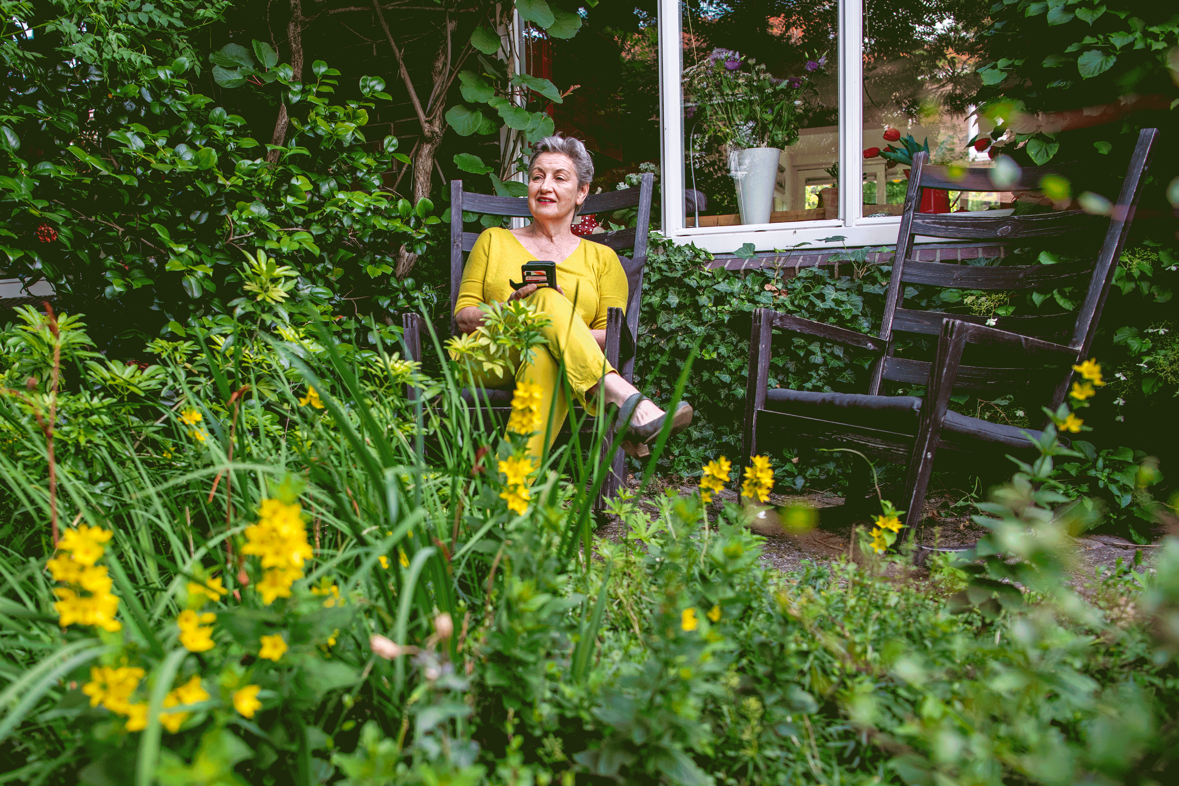 bestuurder van woningcorporatie Mooiland Carly Jansen zit in een tuin met gele bloemen