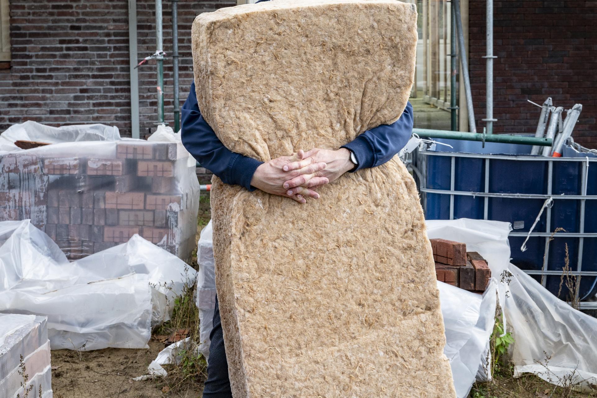 Man die voor huis in aanbouw staat met isolatiemateriaal in zijn armen