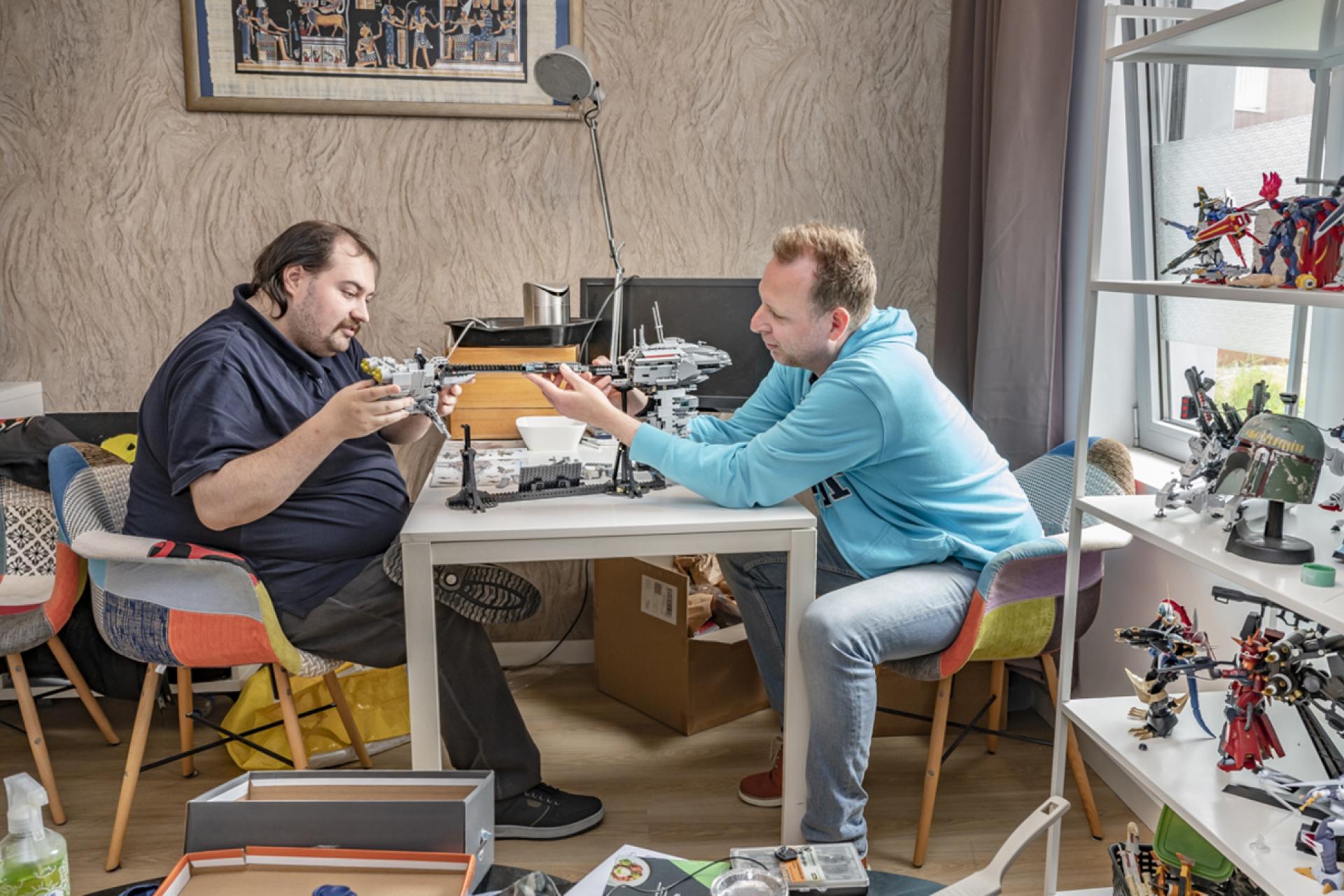 Twee mannen zitten aan een tafel te bouwen met Lego.